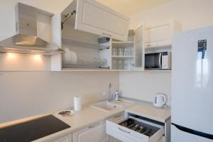 a kitchen with white cabinets and a sink at Apart Petrovskie 1 on Sovetskaya 90 in Tomsk