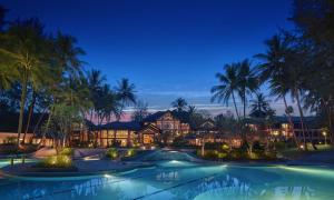 a resort pool with palm trees at night at Dusit Thani Laguna Phuket in Bang Tao Beach