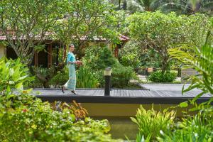a man walking on a walkway in a garden at Dusit Thani Laguna Phuket in Bang Tao Beach
