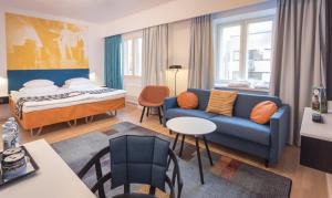 a living room with a blue couch and a bed at Original Sokos Hotel Vaakuna Pori in Pori