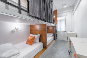 バンコクにあるTiny Taladnoi Hostelの二段ベッド2台、バスルームが備わる小さな客室です。