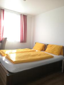 1 cama en un dormitorio con sábanas amarillas y ventana en Landgasthof zum Betenmacher, en Thalgau