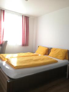 a bed in a bedroom with yellow sheets and a window at Landgasthof zum Betenmacher in Thalgau