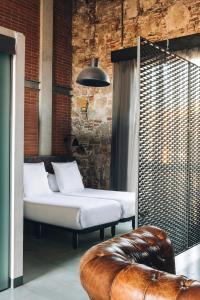 バルセロナにあるバルセロナ アパートメント レプブリカのベッド2台と革張りのソファが備わる客室です。