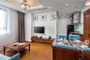 a living room with a dining table and a television at Paris Deli Danang Beach Hotel in Danang
