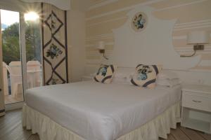 una camera da letto con un letto bianco con due cuscini sopra di Hotel Alexander a Caorle