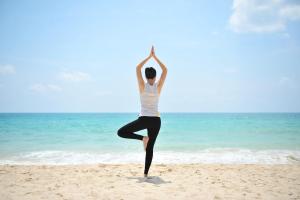 a woman is doing yoga on the beach at Dusit Thani Laguna Phuket in Bang Tao Beach