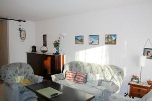 een woonkamer met 2 stoelen, een bank en een tafel bij Residence Arnica in Crans-Montana