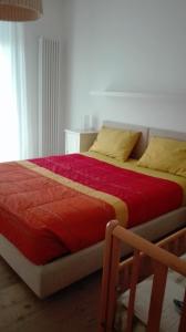 a bedroom with a bed with red sheets and yellow pillows at Appartamento caneve in Arco