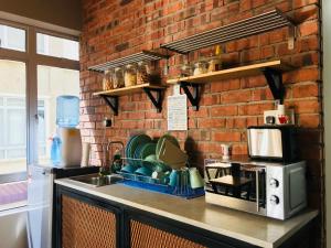 cocina con fregadero y pared de ladrillo en The Good Travelers Hostel - KL Airport, en Sepang