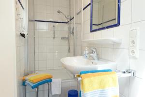 ein weißes Badezimmer mit Waschbecken und Dusche in der Unterkunft Alpschatz Adlerhorst in Oberstdorf + 7 Fotos