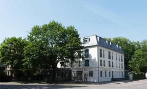 een wit gebouw met een boom ervoor bij Restaurant & Hotel Engelkeller in Memmingen