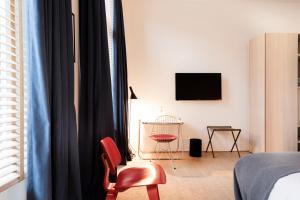 a bedroom with a bed and a chair and a television at Hotel Julien in Antwerp