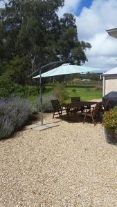 a picnic table with an umbrella and two chairs at Peppermint Farm Cottage in McLaren Vale