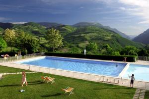 a person standing next to a swimming pool with mountains at Casale Coccinella in Preci