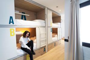 a woman sitting in a room with bunk beds at U-Sense For You Hostel Sevilla in Seville