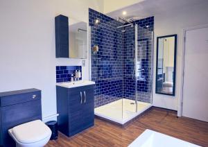 a bathroom with a toilet and a shower with blue tiles at The Old Coffee Tavern in Warwick