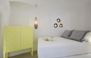 a bedroom with a white bed and a yellow cabinet at Olea Cave House in Imerovigli +13 photos