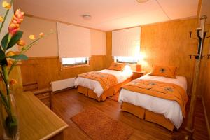 Habitación con 2 camas con edredones de color naranja en Keoken Patagonia, en Puerto Natales