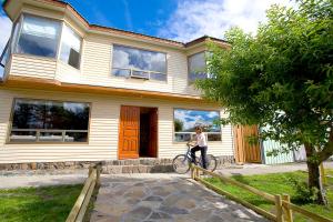 a woman riding a bike in front of a house at Keoken Patagonia in Puerto Natales