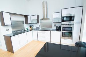 a kitchen with white cabinets and stainless steel appliances at Ocean Serviced Apartments in Edinburgh