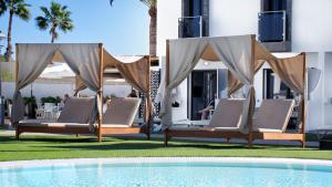 a group of lounge chairs next to a swimming pool at FBC Fortuny Resort - Adults Only in Maspalomas