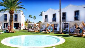 a pool in front of a building with palm trees at FBC Fortuny Resort - Adults Only in Maspalomas