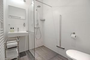 a white bathroom with a shower and a sink at Large 2p canal apartment Prinsengracht in Amsterdam