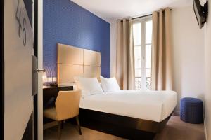 a hotel room with a bed and a desk and a window at Le Relais du Marais in Paris