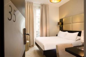 une chambre d'hôtel avec un lit blanc et une fenêtre dans l'établissement Le Relais du Marais, à Paris