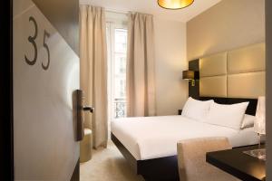 ein Hotelzimmer mit einem weißen Bett und einem Fenster in der Unterkunft Le Relais du Marais in Paris