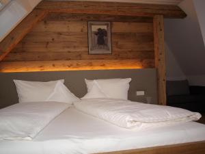 uma cama com lençóis brancos e almofadas num quarto em Hotel Restaurant Peterle em Feldberg