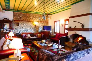 a living room with couches and a stone fireplace at Hotel Papanikola in Piána