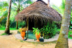 una piccola capanna con un tetto di paglia e alcune piante di Turtle Watch Cabana a Tangalle