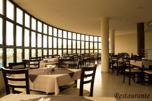 a restaurant with tables and chairs and a large window at Minas Platinum Hotel & Convention in Conselheiro Lafaiete