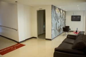 a living room with a couch and a tv on a wall at Minas Platinum Hotel & Convention in Conselheiro Lafaiete