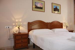 a bedroom with a bed and a nightstand with two lamps at Hostal Carlos 2 in La Línea de la Concepción