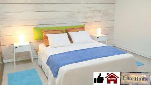 een slaapkamer met een groot wit bed en 2 tafels bij Like Home Gedera in Gedera