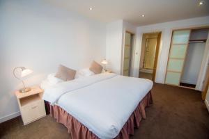 Un dormitorio con una gran cama blanca y una lámpara en Ocean Serviced Apartments, en Edimburgo