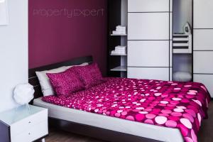 um quarto roxo com uma cama com lençóis e almofadas cor-de-rosa em The Heart of the city em Sófia