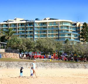 eine Familienwanderung am Strand mit einem Hotel im Hintergrund in der Unterkunft Landmark Resort in Mooloolaba