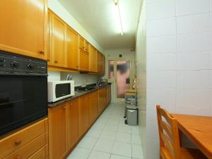 cocina con armarios de madera, mesa y microondas en Apartment Rambla de Tossa by Interhome, en Tossa de Mar