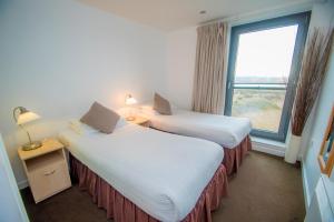 two beds in a hotel room with a window at Ocean Serviced Apartments in Edinburgh