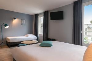 a hotel room with a bed and a tv at Hôtel Sanso by HappyCulture in Paris