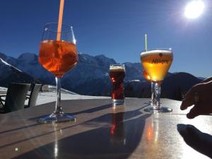 three glasses of beer on a table with mountains in the background at Le Grand Panorama 5 Étage Terrasse Vue sur La Montagne in Saint-Gervais-les-Bains