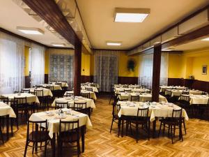 un restaurant avec des tables et des chaises blanches et des murs jaunes dans l'établissement Hotel Slatina, à Lipová-lázně