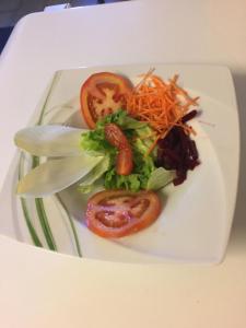 une assiette blanche avec une salade et des carottes dans l'établissement Le Relais des Mayens de Chamoson, à Ovronnaz
