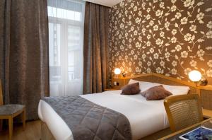 a bedroom with a bed with a floral wallpaper at Logis Hôtel du Midi - Saint Etienne Sud in Saint-Étienne +36 photos