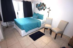 a bedroom with a bed with blue sheets and two chairs at 1004 BLUE OASIS in Honolulu