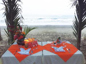 a table on the beach with flowers and wine glasses at Hotel Puerto Gaviota in Tonsupa